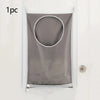 A gray wall-mounted laundry storage bag with a circular opening is displayed against a white wall.