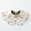 A light beige cotton baby feeding bib with a green lining and a floral pattern.