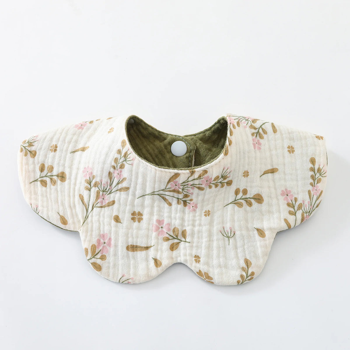 A light beige cotton baby feeding bib with a green lining and a floral pattern.