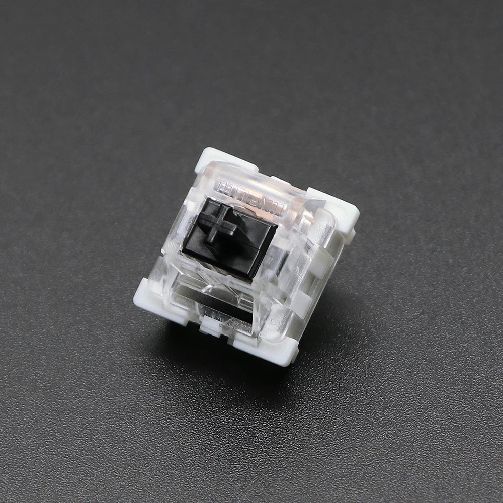 A close-up view of a white mechanical keyboard switch housing with a black plastic stem.