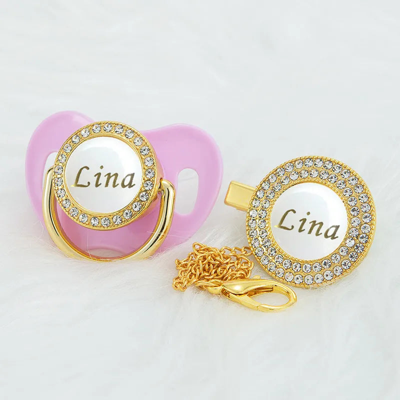 Pink rhinestone pacifier with a clip and a gold chain attached