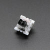 A close-up view of a white 3-pin mechanical keyboard switch housing with a black cross symbol visible inside.