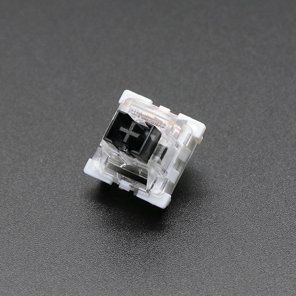A close-up view of a white 3-pin mechanical keyboard switch housing with a black cross symbol visible inside.