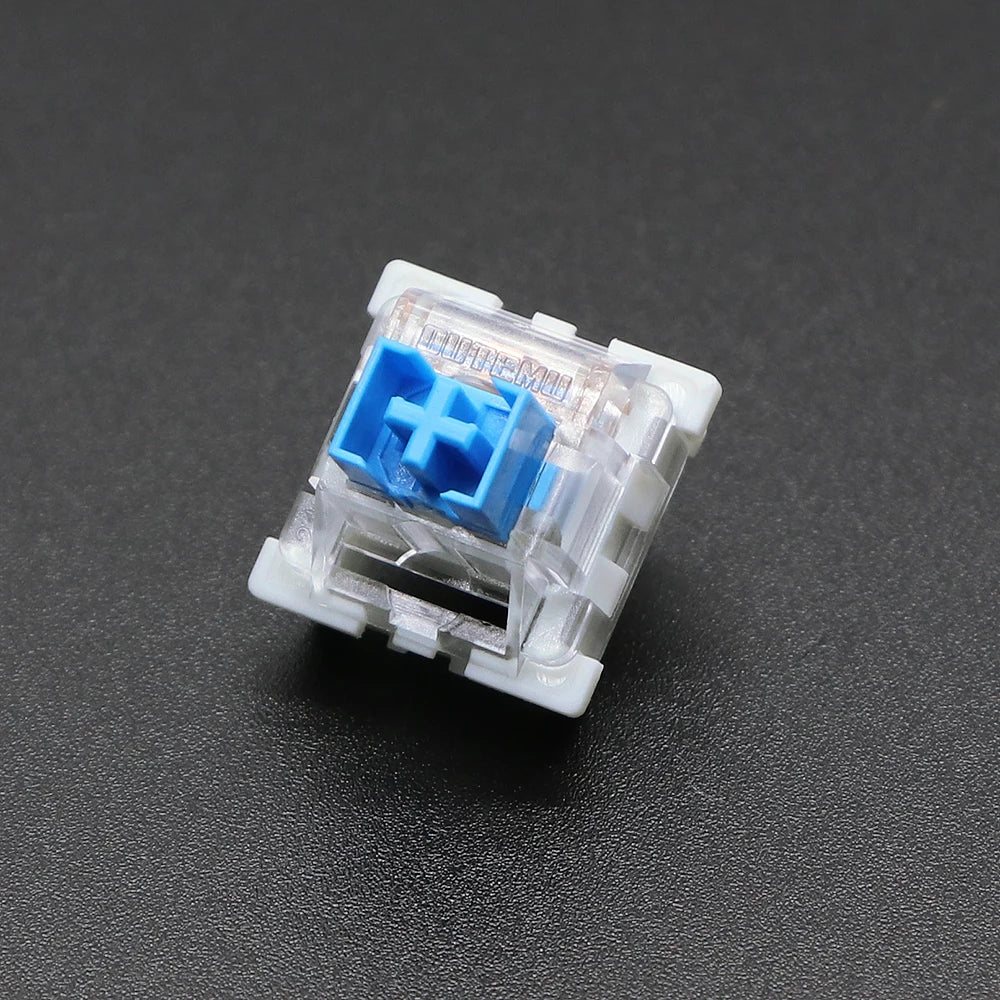 A close-up view of a white plastic 3-pin mechanical keyboard switch with a blue cap and cross symbol.
