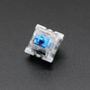 A close-up view of a white mechanical keyboard switch with a blue plastic housing and metal pins.