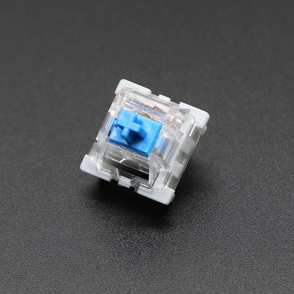 A close-up view of a white mechanical keyboard switch with a blue plastic housing and metal pins.