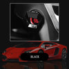 A close-up of an aluminum alloy engine start button cover in black and red on a red sports car interior.