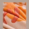 Close-up of an orange and cream textured velvet quilt blanket fabric showing warm, soft fibers.