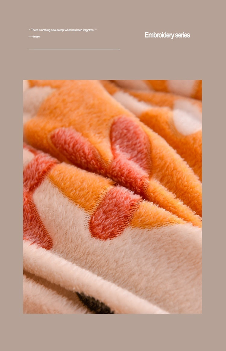 Close-up of an orange and cream textured velvet quilt blanket fabric showing warm, soft fibers.