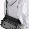 A person is holding a black water-resistant nylon crossbody sling bag against a light gray background.