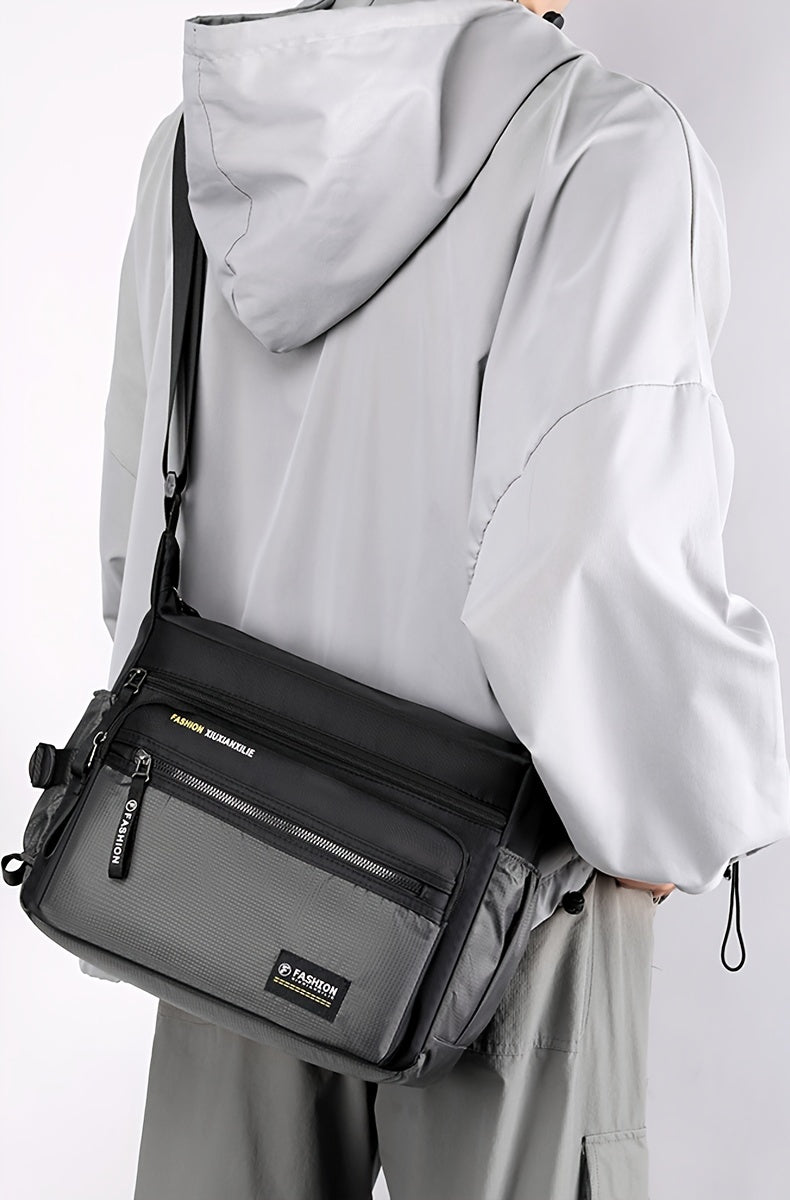 A person is holding a black water-resistant nylon crossbody sling bag against a light gray background.