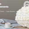 A large bouquet of white hydrangeas is displayed on a table with a candle and glassware.