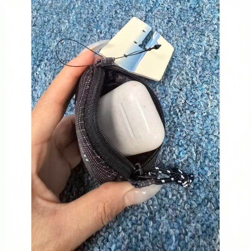 Une main tient un étui de casque en nylon à carreaux et une pochette à clés avec un composant en silicone blanc.