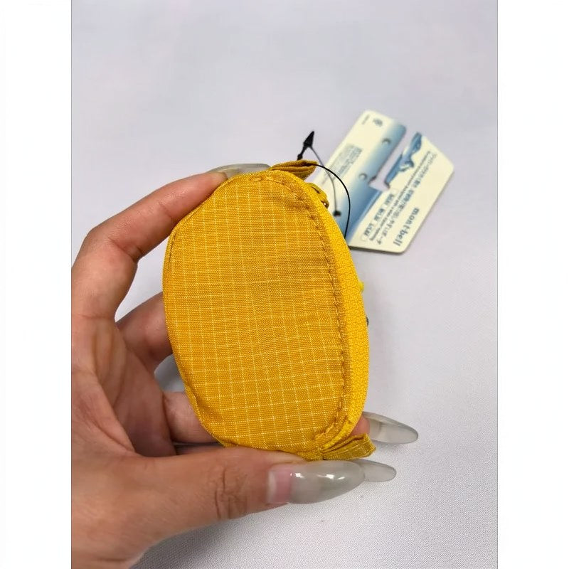 Une main tient un casque en nylon à carreaux jaunes et une pochette de clés sur un fond blanc.