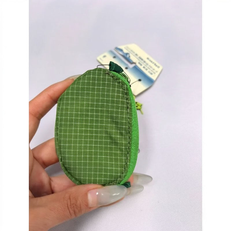 Une main tient un écouteur en nylon à carreaux verts et une pochette de clés sur un fond blanc.