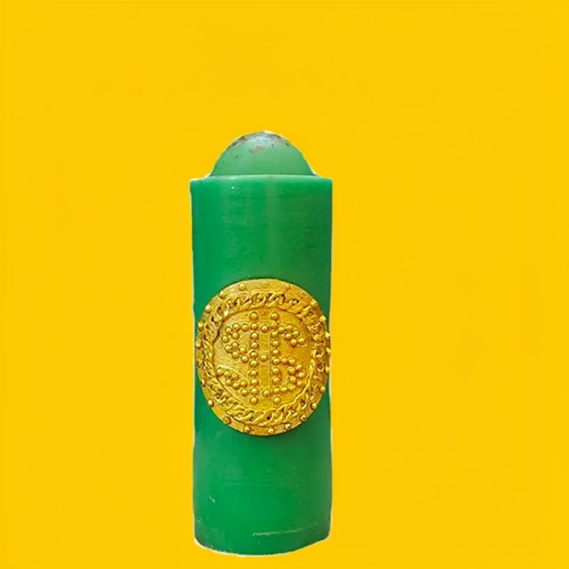 Bougie cylindrique verte haute avec motif circulaire doré sur fond jaune.