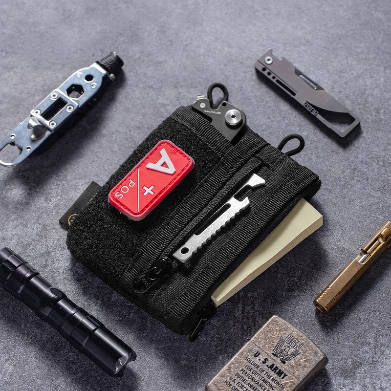 Bolsa organizadora diaria negra con cuchillo y herramientas, mostrada sobre una superficie gris.