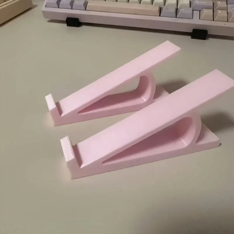 Pink ergonomic keyboard riser with a white non-slip base shown on a desk.