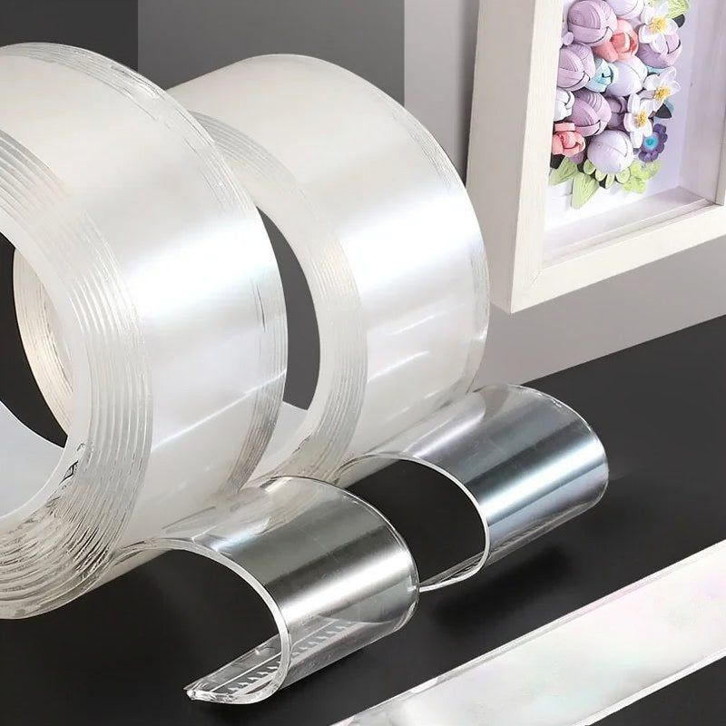 Rouleaux de ruban adhésif nano transparent double face et une bande de ruban argenté présentés sur une surface sombre.