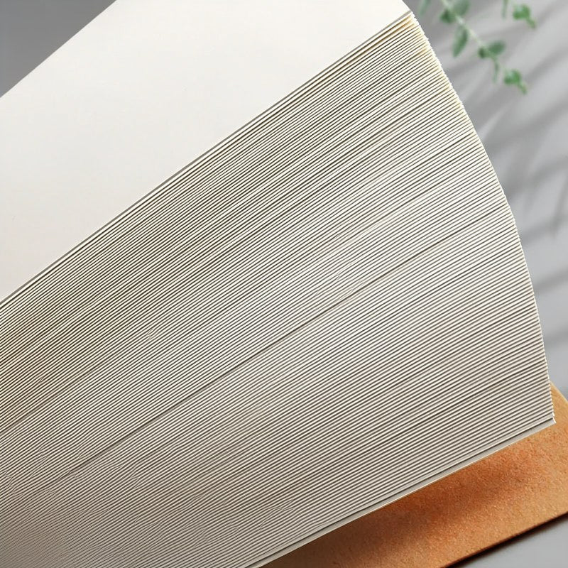 Nahaufnahme eines minimalistischen Kuhfell-Notizbuchs mit beigefarbener Umschlag und dicht beschrifteten weißen Seiten.