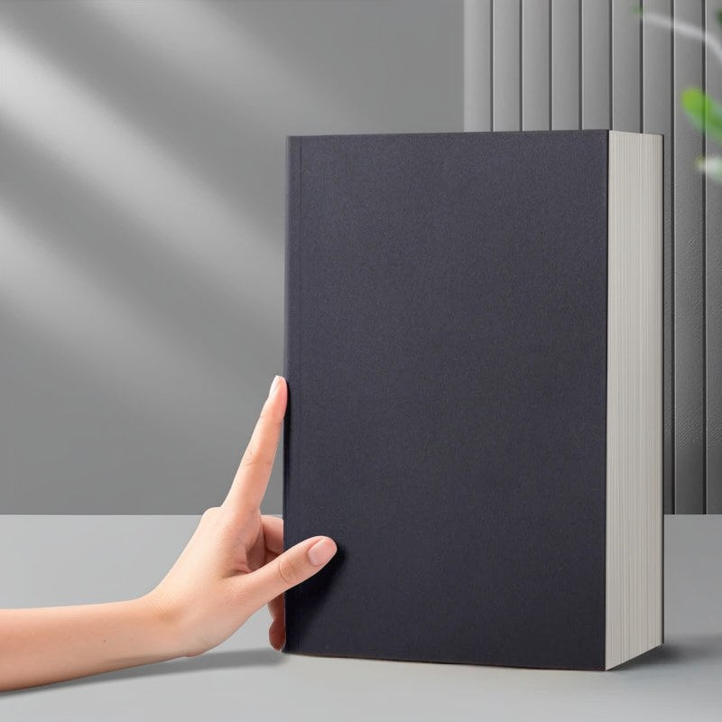 Eine Hand hält ein dunkelgraues, minimalistisches Kuhfell-Notizbuch mit hellem Einband vor grauem Hintergrund.