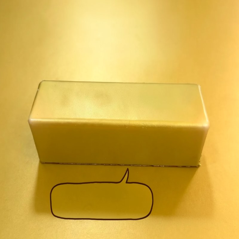 A rectangular yellow fidget stick with a smooth texture is shown against a light yellow background.