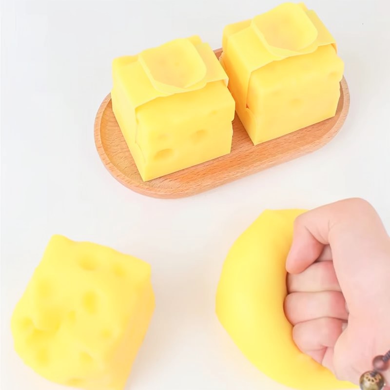 Blocs et jouet anti-stress en forme de fromage jaune sur une surface en bois.