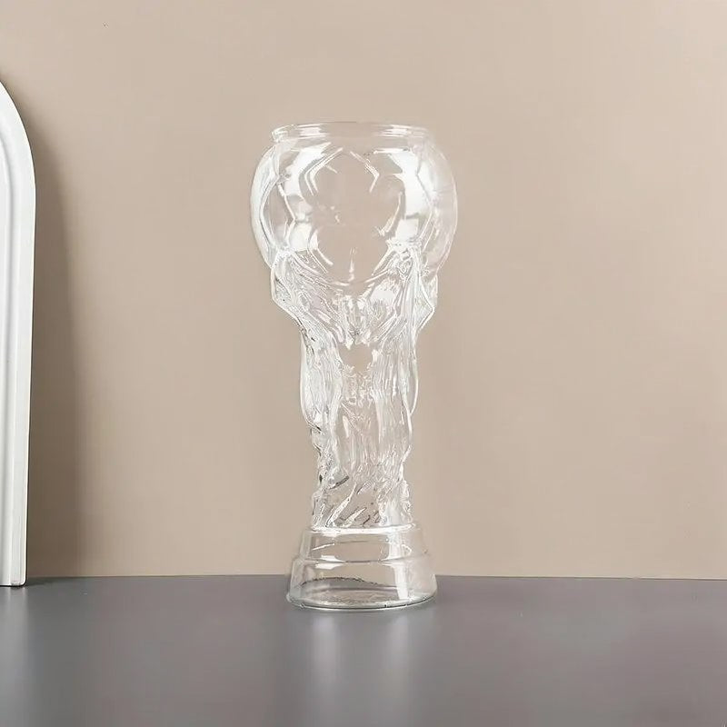 Klares Glaspokal-förmiges Fußballbierglas mit einer geschnitzten Figur auf neutralem Hintergrund.