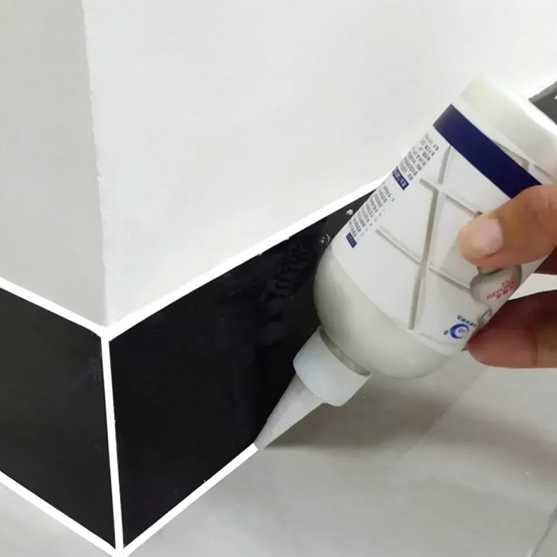 Une main applique un scellant de réparation de joint étanche sur un coin de carreau noir.
