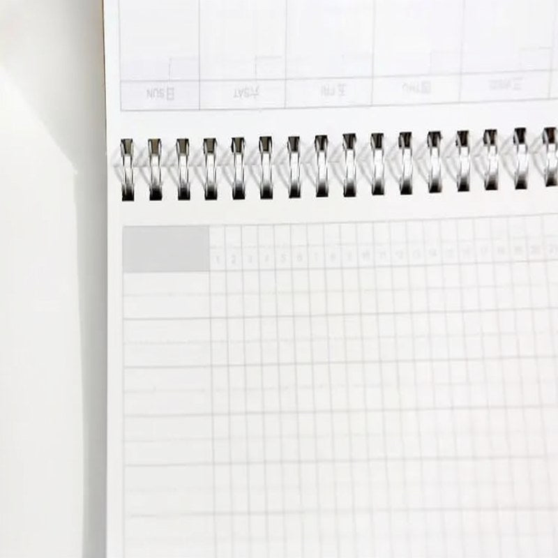 A close-up view of an A5 spiral-bound monthly planner page with ruled lines and a decorative header.