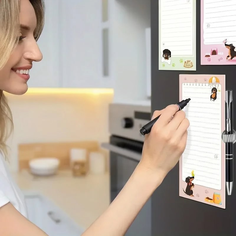 A hand is writing on a magnetic dachshund to-do list notepad with a black pen in a modern kitchen setting.